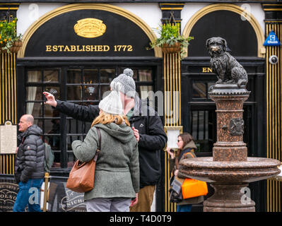 Touristische Paar tragen Bobble hats unter selfie mit Joybergman's Bobby hund Statue, Edinburgh, Schottland, Großbritannien Stockfoto