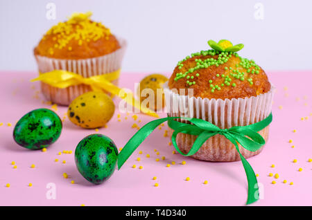 Muffins mit Spachtelmasse besprüht, Blumen, Grün und Gelb Ostern Wachteleier auf Pastell rosa Hintergrund. Kopieren Sie Platz. Close Up. Ostern Holida Stockfoto