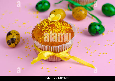 Muffins mit Spachtelmasse besprüht, Blumen, Grün und Gelb Ostern Wachteleier auf Pastell rosa Hintergrund. Kopieren Sie Platz. Close Up. Ostern Holida Stockfoto