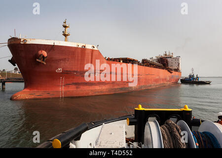 Port Operations für den Transport von Eisenerz. Führende tug von tugboat Schiff-zu-Schiff-STS Liegestelle transhipper am Lader Jetty vor Laden Stockfoto