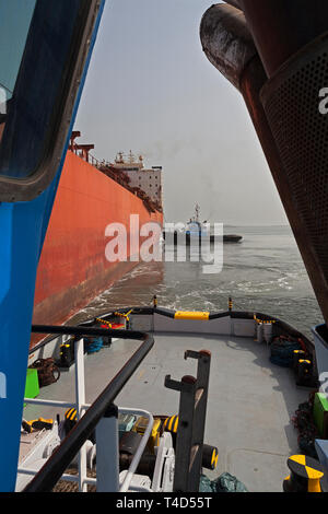 Port Operations für den Transport von Eisenerz. Führende tug von tugboat Schiff-zu-Schiff-STS Liegestelle transhipper am Lader Jetty vor Laden Stockfoto