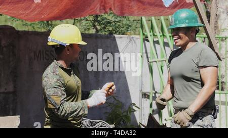 Us Marine Corps Lance Cpl. Mauricio Espinogonzalez (rechts) tauscht Höflichkeiten mit Streitkräfte der Philippinen Armee Pfc. Genesis D. Vargas während einer Pause an Bulsa Grundschule in San Juan, Batangas, Philippinen, 20. März 2019. Dieser Unterricht wird mit den gemeinsamen Anstrengungen der AFP, U.S. Marines, US Air Force gebaut, und die Australian Defence Force als Teil der Übung Balikatan 2019. Balikatan ist eine jährliche militärische Ausbildung Übung durch die Philippinen hosted zwischen AFP und US-Militär, US-amerikanischen und philippinischen Verteidigung Bereitschaft aufzubauen, während strengthenin Stockfoto