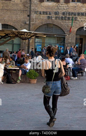 Trendige junge Frau geht über die Piazza Della Cisterna, San Gimignano, Toskana, Italien Stockfoto