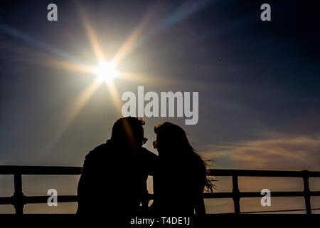 Paar an jedem anderen Blick unter Starburst bei Sonnenuntergang Stockfoto