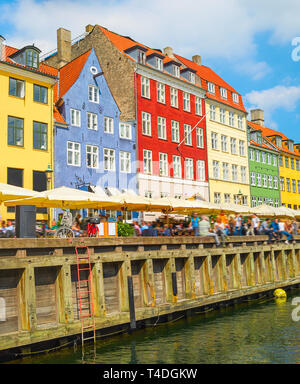 Altstadt mit Blick auf den Hafen Nyhavn in hellen, sonnigen Tag, Touristen zu Fuß und Sitzen in Bars, Cafés, Restaurants, die von Canal, Kopenhagen, Dänemark Stockfoto