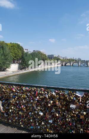 Vorhängeschlösser, Schlösser (Liebe) auf dem Geländer der Brücke über den Fluss Seine in Paris, Frankreich. Sonnigen Sommertag mit blauen Fluss und Himmel im Hintergrund, plus Boulevard ( Stockfoto