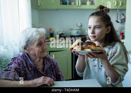 Eine alte Frau Feeds ihrer Enkelin Frühstück. Stockfoto