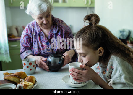 Eine alte Frau Feeds ihrer Enkelin Frühstück. Stockfoto