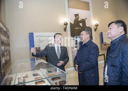 Tim Frank (links), Historiker, Arlington National Cemetery; bietet eine Führung durch die Gedenkstätte Amphitheater Anzeige Zimmer von Verteidigungsminister der Mongolei Nyamaa Enkhbold (Mitte) auf dem Arlington National Cemetery, Arlington, Virginia, 2. April 2019. Enkhbold nahmen an einem bewaffneten Kräfte die volle ehrt Wreath-Laying Zeremonie am Grab des Unbekannten Soldaten und traf mit ANC-Führung als Teil von seinem Besuch. Stockfoto