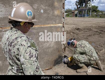 OXNARD, Kalifornien (Mar. 20, 2019) - U.S. Navy Steelworker 2. Klasse Gabriella Gonzalez (links), von Lompoc, Kalifornien, zugeordnet zu den Bau Bataillon Wartungseinheit 303 (CBMU-303), beobachtet Builder 3. Klasse Tyler Jagd, aus Tucson, Arizona, zu CBMU-303 zugewiesen ist, schleifen Sie einen Abschnitt einer expeditionary Kaimauer Patch (PATCH) Curley es zum Schweißen vorzubereiten während ein Proof-of-Concept für einen Test an Bord Naval Base Ventura County zur Unterstützung der Pazifischen Blitz 2019 (PacBlitz 19). Die Curley patch Technik bietet sinnvolle Reparatur zu Piers und Kaianlagen, die militärischen Kräfte, weiterhin die por zu nutzen. Stockfoto