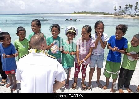 ENNIBURR, Republik der Marshall Inseln (26. März 2019) hinten Adm. Joey Tynch, Commander, Task Force 73, Gespräche mit Marshallese Kinder auf dem Enniburr Pier nach der Ankunft für einen Spatenstich während der Pacific Partnerschaft 2019. Pazifische Partnerschaft, der nun in seinem 14. Iteration, ist die größte jährliche internationale humanitäre Hilfe und Katastrophenhilfe Abwehrbereitschaft Mission im Indopazifik durchgeführt. Jedes Jahr, die Mission Team arbeitet gemeinsam mit Gastgeber und Partner Nationen regionaler Interoperabilität und Disaster Response Funktionen, erhöht die Stabilität und Securit zu verbessern Stockfoto