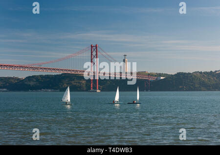 Drei kleine Segelboote am Fluss Tejo mit den 25 April Brücke auf der Hintergrund in der Stadt Lissabon, Portugal Stockfoto