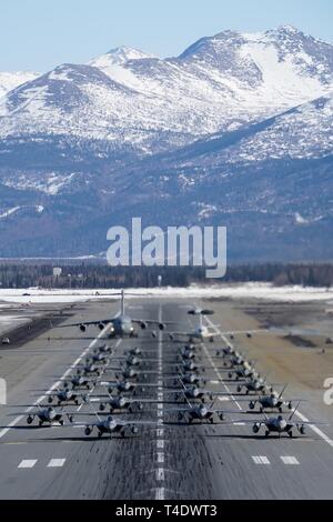 F-22 Raptors aus der 3 Flügel und 477th Fighter Group beteiligen sich in einer engen Formation Taxi mit einem E-3 Sentry und eine C-17 Globemaster III, bekannt als ein Elephant Walk, 26. März 2019, während eines Polar Kraft Übung in Joint Base Elmendorf-Richardson, Alaska. Dieser zweiwöchige Übung gibt staffeln die Möglichkeit, ihre Fähigkeiten unter Beweis zu stellen, Bereitstellen und liefern überwältigende bekämpfen Airpower. Stockfoto