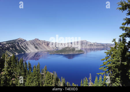 A view of the beautiful clear Crater Lake showing the deep blue water, trees, and Wizard Island. Crater Lake National Park, Oregon. Stockfoto