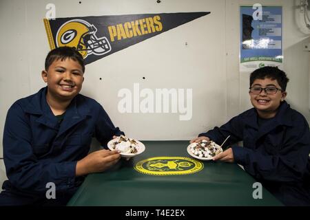 Philippinischen MEER (26. März 2019) Rylan Scott, Links, und Kayden Scott posieren für ein Foto mit ihrem Eis als Teil eines Tiger Kreuzfahrt an Bord des amphibious Transport dock Schiff USS Green Bay LPD (20). Tiger Kreuzfahrten sind eine Chance für die Gäste ein US-Schiff der Marine zu reiten und zu erfahren, was das Leben ist wie für die US-Navy Matrosen auf See. Green Bay, Teil der Wasp Amphibious Ready-Gruppe, die in der Region die Interoperabilität mit Partnern zu verbessern und dienen als eine tödliche bereit - Response Force für jede Art von Kontingenz. Stockfoto