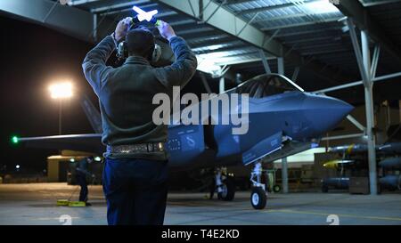 Einen Flieger von 421St Aircraft Maintenance Unit des 388 Fighter Wing Marschälle einer F-35A Lightning II während der Nacht Flugbetrieb bei Hill Air Force Base, Ohio, 26. März 2019. Nacht fliegen ist für Piloten, die ihre Kampffähigkeiten und Betreuer rund um die Uhr arbeit Düsen für Flug vorbereiten zu schärfen, Sie prüfen nach dem Flug, und Sie für den nächsten Flugtag bereit. Die 388 Fighter Wing ist der Air Force combat-codierte F-35 ein Flügel. Stockfoto