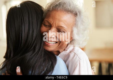 Blick über die Schulter des älteren Mutter umarmte von erwachsenen Tochter zu Hause Stockfoto