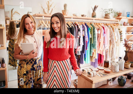 Portrait von zwei weiblichen Assistenten mit digitalen Tablet Arbeiten in Kleidung und Geschenke Shop Stockfoto