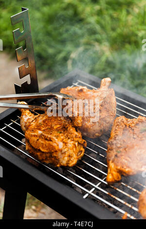 Flipping Huhn über verbleibende Seite auf kleinen Hinterhof Grill zu kochen. Stockfoto