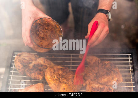 Bürsten extra marinierten Soße auf Holzkohle Huhn. Stockfoto