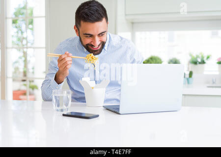 Business mann Essen asiatische Küche Lieferung während der Arbeit mit dem Laptop im Büro Stockfoto