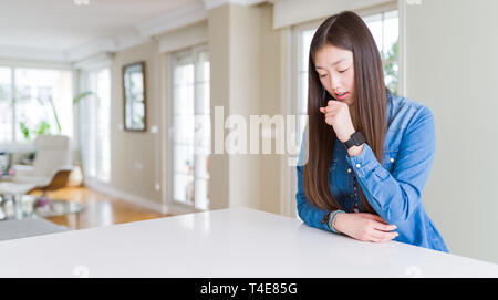 Junge schöne asiatische Frau mit langem Haar zu tragen Jeansjacke Unwohlsein und Husten als Symptom für kalte oder Bronchitis. Healthcare Konzept. Stockfoto