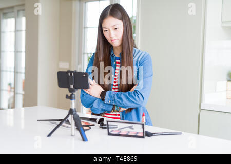 Schöne asiatische Einflussnehmer Frau Aufnahme Make-up Tutorial über Smartphone-kamera Skeptiker und nervös, Missbilligenden Ausdruck auf dem Gesicht mit gekreuzten Stockfoto