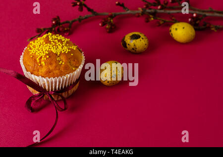 Ostern Muffin mit Schleife dekoriert und besprüht, gefärbte Eier und ein Zweig der Aprikosenbaum auf dunklem Rosa oder Pink Hintergrund. Kopieren Sie Platz. Greetin Stockfoto
