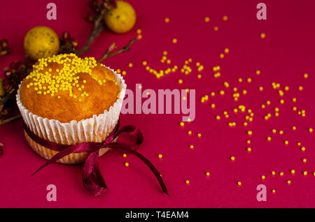 Ostern Muffin mit Schleife dekoriert und besprüht, gelb Wachteleier und ein Zweig der Aprikosenbaum auf dunklem Rosa oder Pink Hintergrund. Platz für Text Stockfoto