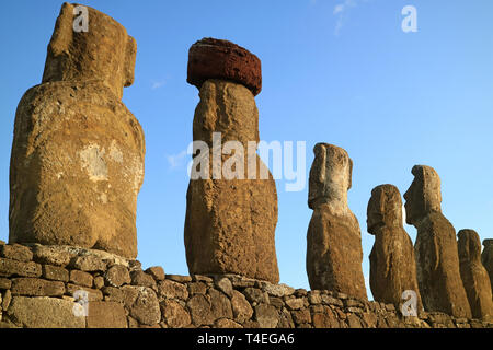 Rückseite des gigantischen Moai Statuen am Ahu Tongariki, eins mit dem obersten Knoten namens Pukao aus roten Schlacken, archäologische Stätte in Easter Island, Chile Stockfoto