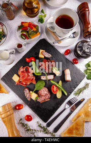 Restaurant Frühstück mit leckeren Salami, Stücke von geschnittenen Prosciutto mit schwarzer Tee serviert. Stockfoto