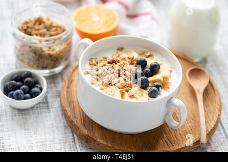 Gesundes Frühstück Müsli Müsli mit Milch und Obst in einer Schüssel auf hölzernen Tisch Hintergrund. Detailansicht, selektiver Fokus Stockfoto