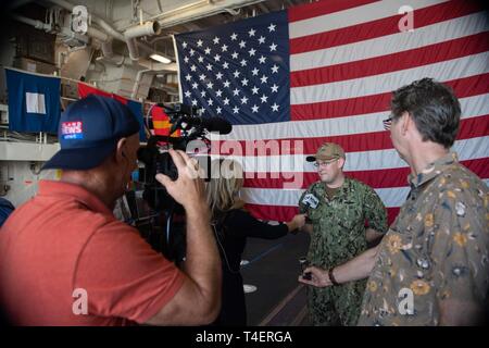 PEARL Harbor, Hawaii (Apr. 2, 2019) Feuer 1. Klasse Timothy Luckritz Controlman, von Richland, Mo. ist von den Reportern im Hangar Bucht von Geführte interviewt Anti-raketen-Zerstörer USS Zumwalt (DDG 1000). Zumwalt leitet den Hafen besuchen Sie als Teil ihrer Routinetätigkeiten im östlichen Pazifik. Zumwalt Klasse Zerstörer bieten die Marine mit agilen militärische Vorteile im Meer und mit Bodentruppen an Land. Stockfoto