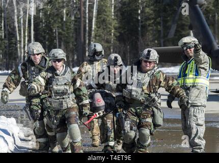 Verteidiger aus der 176 Sicherheitskräfte Squadron tragen einen simulierten Patienten während eines Unfalls Evakuierung Übung während der Defender Agile Combat Beschäftigung bei Joint Base Elmendorf-Richardson, Alaska, 28. März 2019. Die ACE-Übung präsentierten Kampftruppe Bereitschaft während der Kämpfe in der chemischen, biologischen, radiologischen und nuklearen Verteidigung Schutzausrüstung. Stockfoto