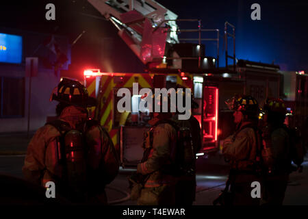 Ontario Kanada 13. April 2019: feuerwehrleute stehen, indem Sie warten, um zu helfen, einen Brand in der Stadt kämpfen. Feuerwehrmänner und Feuerwehrauto mit Blaulicht an. Stockfoto