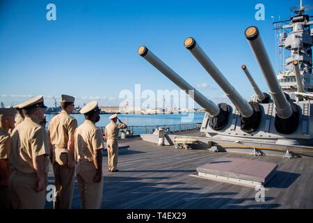 PEARL Harbor, Hawaii (Apr. 4, 2019) Kapitän Andrew Carlson, kommandierender Offizier der geführte Anti-raketen-Zerstörer USS Zumwalt (DDG 1000), begrüßt während der Morgen Farben an Bord der USS Missouri Memorial. Zumwalt leitet den Hafen besuchen Sie als Teil ihrer Routinetätigkeiten im östlichen Pazifik. Zumwalt Klasse Zerstörer bieten die Marine mit agilen militärische Vorteile im Meer und mit Bodentruppen an Land. Stockfoto