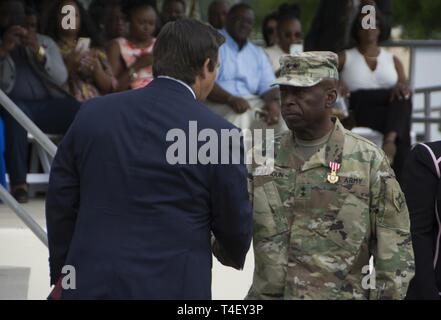 Reg. Ron DeSantis, Oberbefehlshaber der Florida National Guard, präsentiert die die Florida Kreuz Generalmajor Michael Calhoun, ausgehende Adjutant General von Florida, die während eines Befehls Zeremonie im Camp Blanding gemeinsame Training Center am 6. April. Calhoun verdient die Auszeichnung für besonders verdienstvollen Service während seiner Amtszeit als Adjutant General. Stockfoto