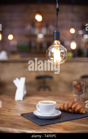 Lecker Tasse Latte Macchiato mit köstlichem Croissant in einem vintage Coffee Shop. Holztisch. Unscharfer Hintergrund. Stockfoto
