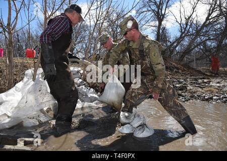 Army Staff Sgt. Jashua Trulson, rechts, und Sgt. Tyler Schlick, sowohl der 188 Ingenieur Unternehmen, Wahpeton, N.D., Hochwasser, wie sie Sandsäcke statt Wasser aus die Sicherung durch eine Drainage Düker in einem Bauernhof im ländlichen Cass County, in der Nähe von West Fargo, N.D., April 8, 2019. Sie sind Teil einer North Dakota Army National Guard Quick Response Force (Qrf) Team reagiert auf einen Notfall Sandsack Antrag der Hauseigentümer. Der Guard Quick Reaction Force (Qrf) hat 8 Missionen und weiterhin stehen an der Streitkräfte finden Zentrum am nördlichen Rand von Fargo, wenn zusätzliche Stockfoto