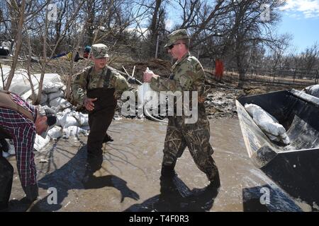 Army Staff Sgt. Jashua Trulson, rechts, und Sgt. Tyler Schlick, sowohl der 188 Ingenieur Unternehmen, Wahpeton, N.D., Hochwasser, wie sie Sandsäcke statt Wasser aus die Sicherung durch eine Drainage Düker in einem Bauernhof im ländlichen Cass County, in der Nähe von West Fargo, N.D., April 8, 2019. Sie sind Teil einer North Dakota Army National Guard Quick Response Force (Qrf) Team reagiert auf einen Notfall Sandsack Antrag der Hauseigentümer. Der Guard Quick Reaction Force (Qrf) hat 8 Missionen und weiterhin stehen an der Streitkräfte finden Zentrum am nördlichen Rand von Fargo, wenn zusätzliche Stockfoto