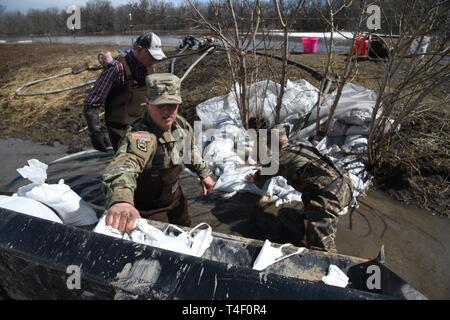 Army Staff Sgt. Jashua Trulson, rechts, und Sgt. Tyler Schlick, sowohl der 188 Ingenieur Unternehmen, Wahpeton, N.D., Hochwasser, wie sie Sandsäcke statt Wasser aus die Sicherung durch eine Drainage Düker in einem Bauernhof im ländlichen Cass County, in der Nähe von West Fargo, N.D., April 8, 2019. Sie sind Teil einer North Dakota Army National Guard Quick Response Force (Qrf) Team reagiert auf einen Notfall Sandsack Antrag der Hauseigentümer. Der Guard Quick Reaction Force (Qrf) hat 8 Missionen und weiterhin stehen an der Streitkräfte finden Zentrum am nördlichen Rand von Fargo, wenn zusätzliche Stockfoto