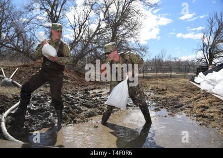 Army Staff Sgt. Jashua Trulson, rechts, und Sgt. Tyler Schlick, sowohl der 188 Ingenieur Unternehmen, Wahpeton, N.D., Hochwasser, wie sie Sandsäcke statt Wasser aus die Sicherung durch eine Drainage Düker in einem Bauernhof im ländlichen Cass County, in der Nähe von West Fargo, N.D., April 8, 2019. Sie sind Teil einer North Dakota Army National Guard Quick Response Force (Qrf) Team reagiert auf einen Notfall Sandsack Antrag der Hauseigentümer. Der Guard Quick Reaction Force (Qrf) hat 8 Missionen und weiterhin stehen an der Streitkräfte finden Zentrum am nördlichen Rand von Fargo, wenn zusätzliche Stockfoto