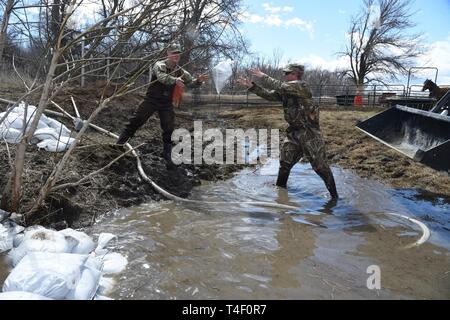 Army Staff Sgt. Jashua Trulson, rechts, und Sgt. Tyler Schlick, sowohl der 188 Ingenieur Unternehmen, Wahpeton, N.D., Hochwasser, wie sie Sandsäcke statt Wasser aus die Sicherung durch eine Drainage Düker in einem Bauernhof im ländlichen Cass County, in der Nähe von West Fargo, N.D., April 8, 2019. Sie sind Teil einer North Dakota Army National Guard Quick Response Force (Qrf) Team reagiert auf einen Notfall Sandsack Antrag der Hauseigentümer. Der Guard Quick Reaction Force (Qrf) hat 8 Missionen und weiterhin stehen an der Streitkräfte finden Zentrum am nördlichen Rand von Fargo, wenn zusätzliche Stockfoto