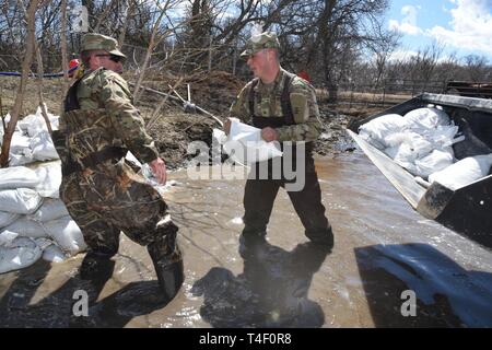 Armee Sgt. Tyler Schlick, rechts, und Staff Sgt. Jashua Trulson, sowohl der 188 Ingenieur Unternehmen, Wahpeton, N.D., Hochwasser, wie sie Sandsäcke statt Wasser aus die Sicherung durch eine Drainage Düker in einem Bauernhof im ländlichen Cass County, in der Nähe von West Fargo, N.D., April 8, 2019. Sie sind Teil einer North Dakota Army National Guard Quick Response Force (Qrf) Team reagiert auf einen Notfall Sandsack Antrag der Hauseigentümer. Der Guard Quick Reaction Force (Qrf) hat 8 Missionen und weiterhin stehen an der Streitkräfte finden Zentrum am nördlichen Rand von Fargo, wenn zusätzliche Stockfoto