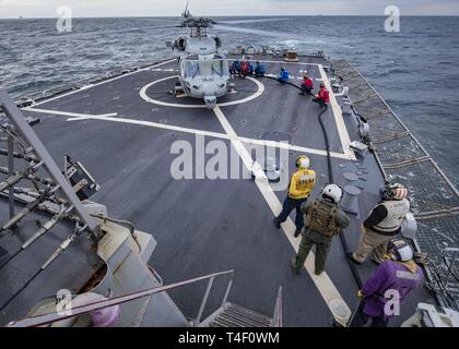 Ozean (April 7, 2019) - Matrosen an Bord der Arleigh-Burke-Klasse geführte-missile Destroyer tanken einen MH-60S Seahawk, zu der "Ritter" der Hubschrauber Meer Combat Squadron (HSC) 22, während der übung Gemeinsame Krieger 19-1, 7. April 2019 vergeben. Gemeinsame Krieger ist ein Vereinigtes Königreich - led, multinationale Übung in einem robusten maritime Ausbildung Umfeld, in dem die Verbündeten und Partnern Interoperabilität verbessern kann und Kräfte für kombinierte Operationen vorzubereiten. Stockfoto