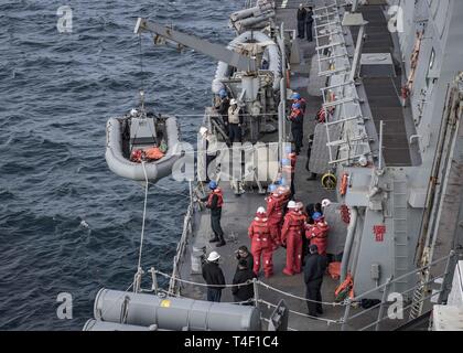 Ozean (8. April 2019) Matrosen an Bord der Arleigh Burke stationiert - geführte Anti-raketen-Zerstörer USS Carney (DDG64) Mann das Boot Deck für ein entgegenkommendes Personal Transfer von der britischen Royal Navy Astute-Klasse nuklearen U-Boot Flotte HMS Hinterhalt während der Übung gemeinsame Krieger 19-1, 8. April 2019. Gemeinsame Krieger ist ein Vereinigtes Königreich - led, multinationale Übung in einem robusten maritime Ausbildung Umfeld, in dem die Verbündeten und Partnern Interoperabilität verbessern kann und Kräfte für kombinierte Operationen vorzubereiten. Stockfoto