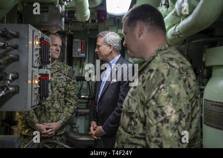 NORFOLK, Virginia (April 8, 2019) - Herr Gregory Slawischen, Assistant Secretary der Marine, Gespräche mit Kapitän Marty Mucklan, Commodore, Submarine Squadron Six und Cdr. Wird Willey, Kommandierender Offizier, USS John Warner (SSN785), während einer Tour an Bord der John Warner, 8. April 2019. Slawische ist zuständig für die Überwachung und Kontrolle von Arbeitskräften und finden allgemeine Angelegenheiten der Abteilung der Marine, einschließlich der Entwicklung der Programme und der Politik, die an Soldaten, deren Angehörige und die zivilen Mitarbeiter. Stockfoto