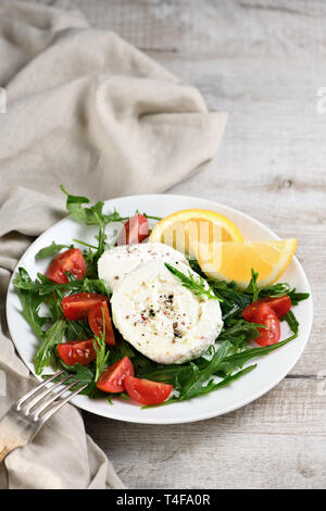 Mozzarella Salat mit Ruccola, Tomaten, Zitrone, abgeschmeckt mit Gewürzen und Olivenöl Stockfoto