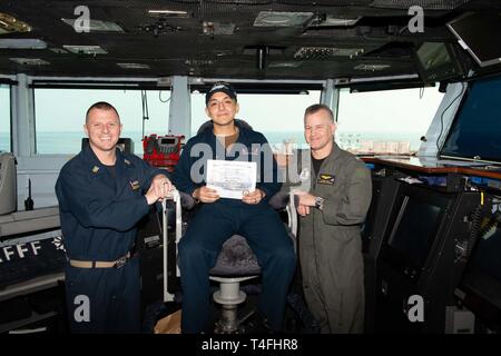 Us-Schiff der Marine Offizier Seaman Salvador Gonzalezpino, von Chicago, posiert für ein Foto wie die Segler des Tages mit Kapitän Randy Peck, rechts, kommandierender Offizier der Flugzeugträger USS John C Stennis (CVN 74) und Command Master Chief Benjamin Hetzen in den Golf von Aden, 10. April 2019. Die John C Stennis Carrier Strike Group ist in die USA 5 Flotte Bereich der Maßnahmen zur Unterstützung der Marine im Einsatz für die Stabilität und Sicherheit in der Region zu gewährleisten und verbindet das Mittelmeer und den Pazifischen Raum durch den westlichen Indischen Ozean und drei strategische Choke poin Stockfoto