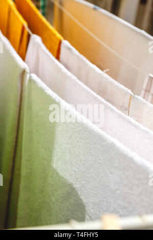 Weiße und farbige Bettwäsche und Handtücher auf der Wäscheleine getrocknet werden. Stockfoto